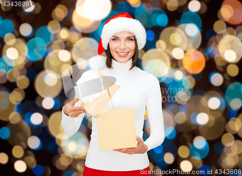 Image of smiling woman in santa hat opening christmas gift