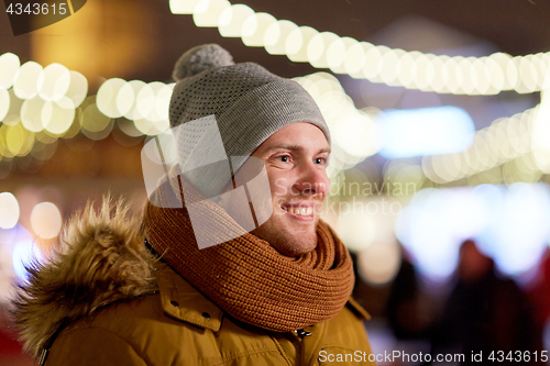 Image of happy young man over christmas lights in winter