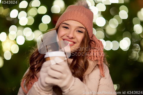 Image of happy woman with coffee over christmas lights