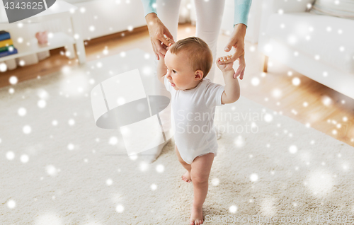 Image of happy baby learning to walk with mother help