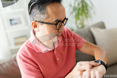 Image of close up of asian man with smart watch at home