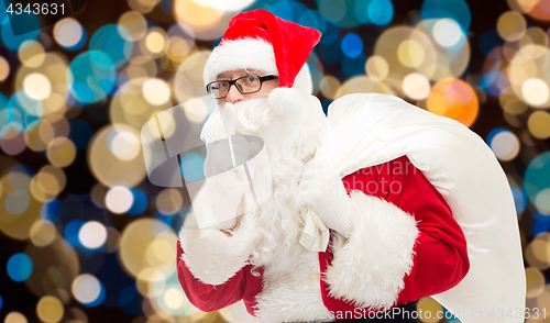 Image of santa claus with gifts bag over christmas lights