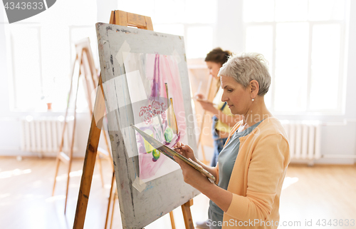 Image of woman artist with easel painting at art school