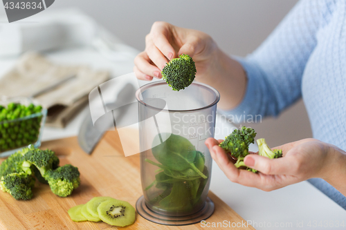 Image of woman hand adding broccoli to measuring cup