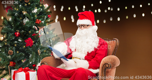 Image of santa claus with tablet pc and christmas tree