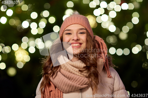 Image of happy young woman over christmas tree lights