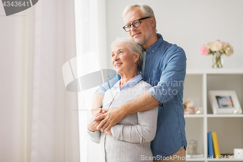 Image of happy senior couple looking through window at home