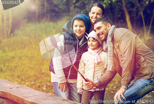 Image of happy family with smartphone selfie stick at camp