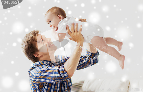 Image of happy young father playing with baby at home