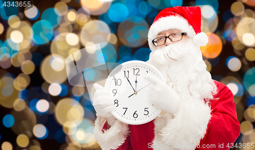 Image of santa claus with twelve on clock at christmas