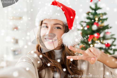 Image of happy woman taking selfie over christmas tree