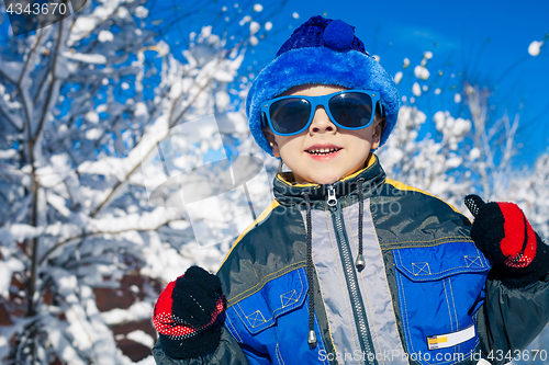 Image of Happy little boy playing  on winter snow day.