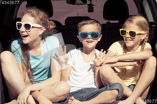 Image of Happy brother and his two sisters are sitting in the car at the 