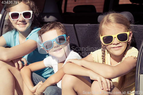 Image of Happy brother and his two sisters are sitting in the car at the 