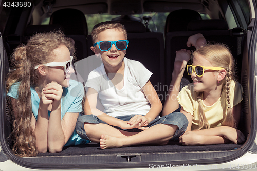 Image of Happy brother and his two sisters are sitting in the car at the 