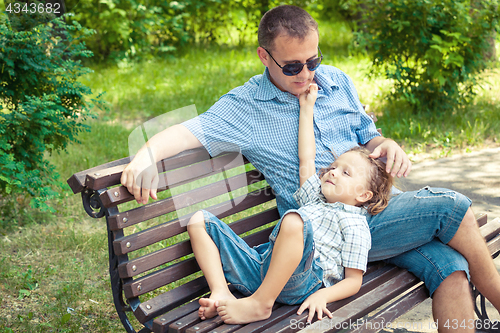 Image of Father and son playing at the park on bench at the day time.