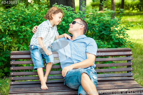 Image of Father and son playing at the park on bench at the day time.