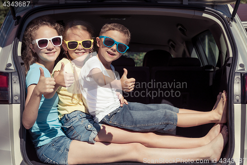 Image of Happy brother and his two sisters are sitting in the car at the 