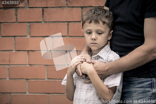 Image of Portrait of young sad little boy and father sitting outdoors at 