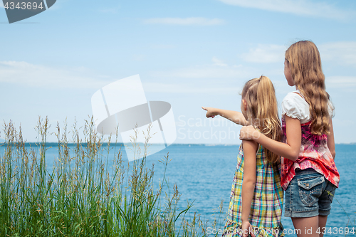 Image of Two sisters  playing on the beach at the day time.