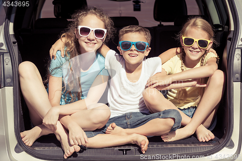 Image of Happy brother and his two sisters are sitting in the car at the 