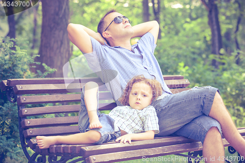 Image of Father and son playing at the park on bench at the day time.