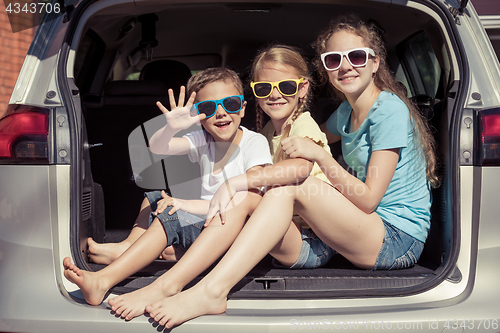 Image of Happy brother and his two sisters are sitting in the car at the 