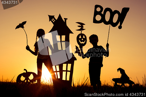 Image of Happy brother and  sister playing outdoors at the sunset time.