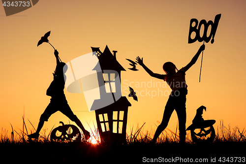 Image of Happy brother and  sister playing outdoors at the sunset time.