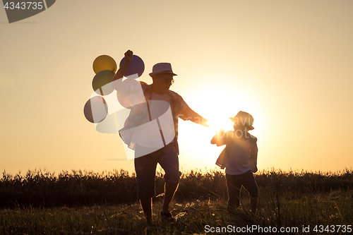 Image of Father and son running on the road at the sunset time.