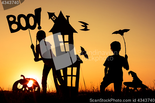 Image of Happy brother and  sister playing outdoors at the sunset time.