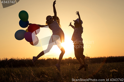 Image of Silhouette of two happy children which playing on the field at t