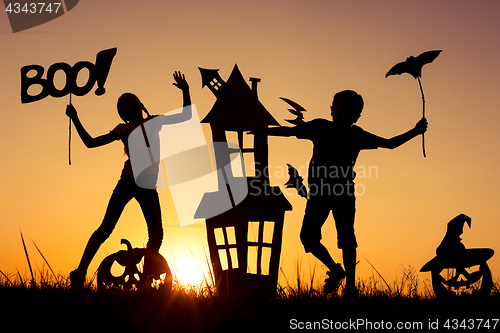 Image of Happy brother and  sister playing outdoors at the sunset time.