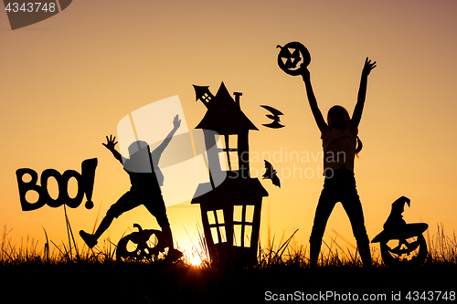 Image of Happy brother and  sister playing outdoors at the sunset time.