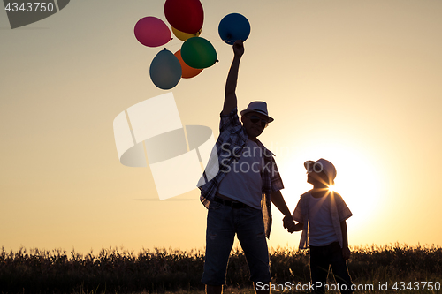 Image of Father and son standing on the road at the sunset time.