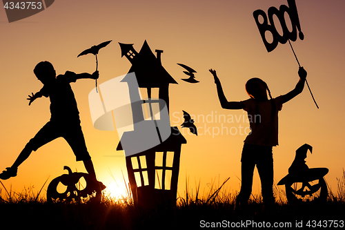 Image of Happy brother and  sister playing outdoors at the sunset time.