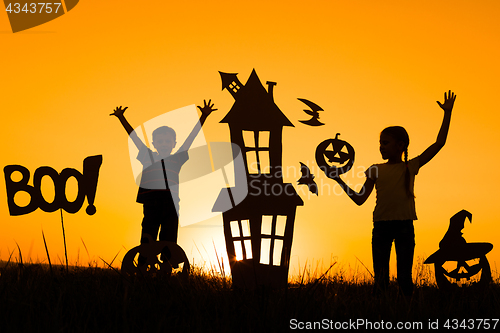 Image of Happy brother and  sister playing outdoors at the sunset time.