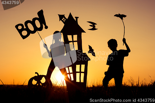 Image of Happy brother and  sister playing outdoors at the sunset time.