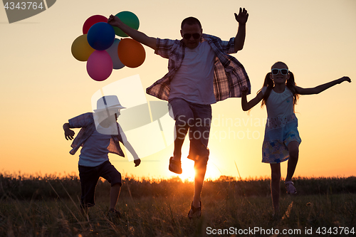 Image of Father and children running on the road at the sunset time.