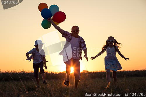 Image of Father and children running on the road at the sunset time.