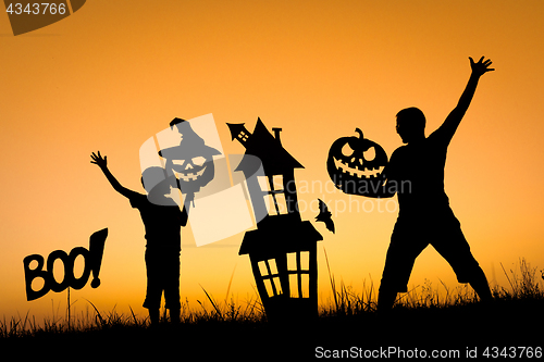 Image of Happy father and son playing outdoors at the sunset time.