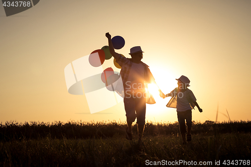 Image of Father and son running on the road at the sunset time.