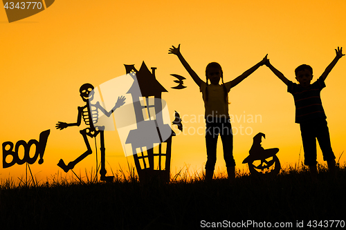 Image of Happy brother and  sister playing outdoors at the sunset time.