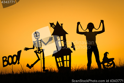 Image of Happy little girl playing outdoors at the sunset time.