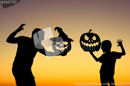 Image of Happy father and son playing outdoors at the sunset time.