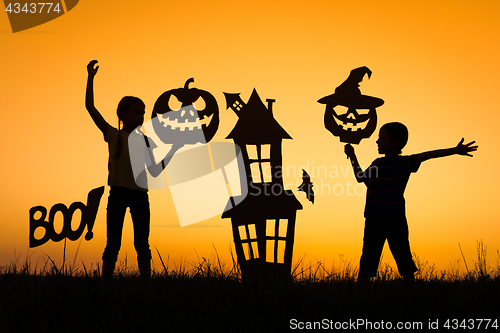 Image of Happy brother and  sister playing outdoors at the sunset time.