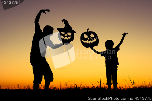 Image of Happy father and son playing outdoors at the sunset time.