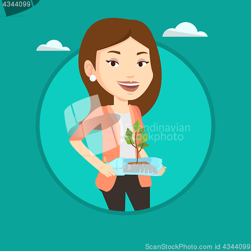 Image of Woman holding plant growing in plastic bottle.
