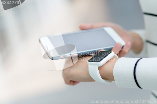 Image of Woman connecting smart watch and cellphone