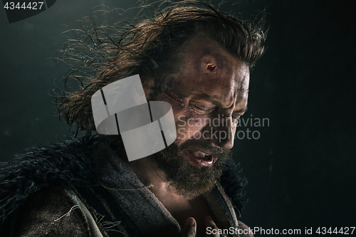 Image of Portrait of a brutal bald-headed viking in a battle mail posing against a black background.